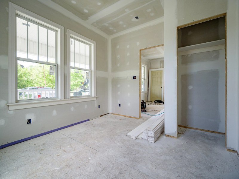 A bright room in a home being renovated, with fresh plasterboard walls